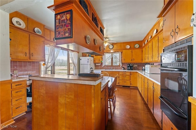 kitchen with light countertops, decorative backsplash, white appliances, a warming drawer, and a ceiling fan