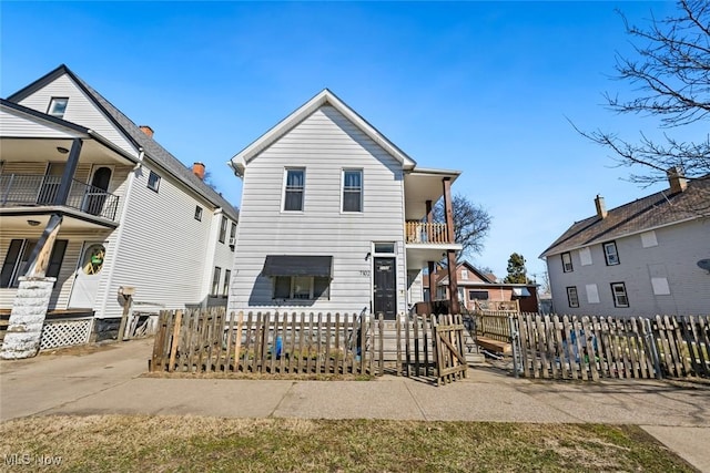 rear view of property featuring a fenced front yard and a balcony