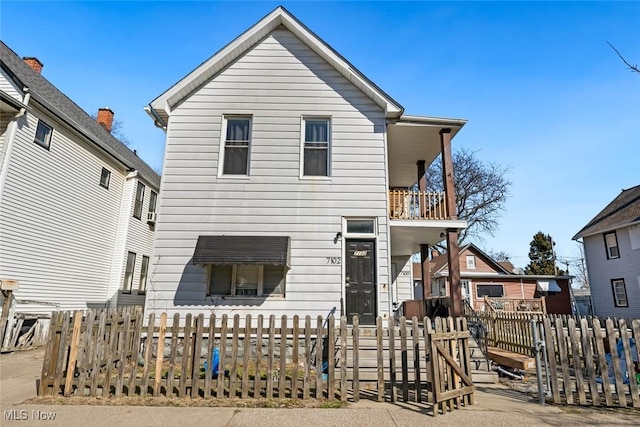 view of front of house featuring a balcony and a fenced front yard