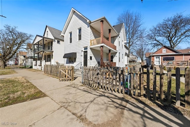 view of front of house with a balcony, a residential view, and a fenced front yard