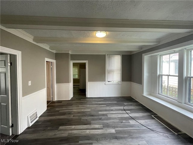 unfurnished room with a wainscoted wall, beam ceiling, a textured ceiling, and visible vents