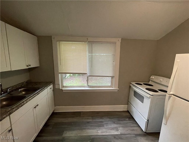 kitchen featuring a sink, dark countertops, dark wood finished floors, white appliances, and baseboards