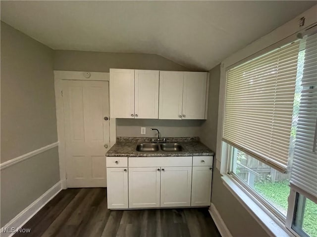 kitchen with baseboards, dark wood finished floors, lofted ceiling, white cabinets, and a sink