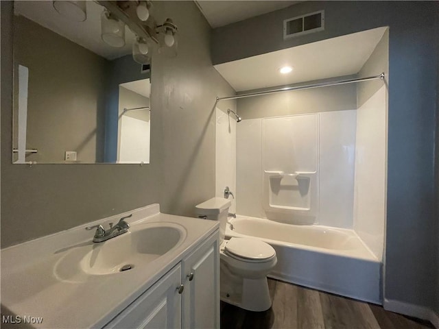 bathroom with vanity, wood finished floors, visible vents, bathing tub / shower combination, and toilet