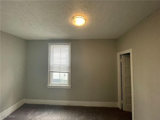 empty room featuring a textured ceiling, baseboards, and carpet floors