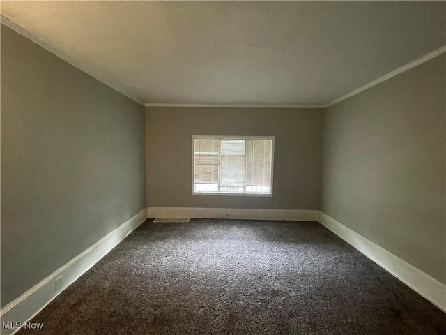 spare room featuring dark carpet, baseboards, and ornamental molding