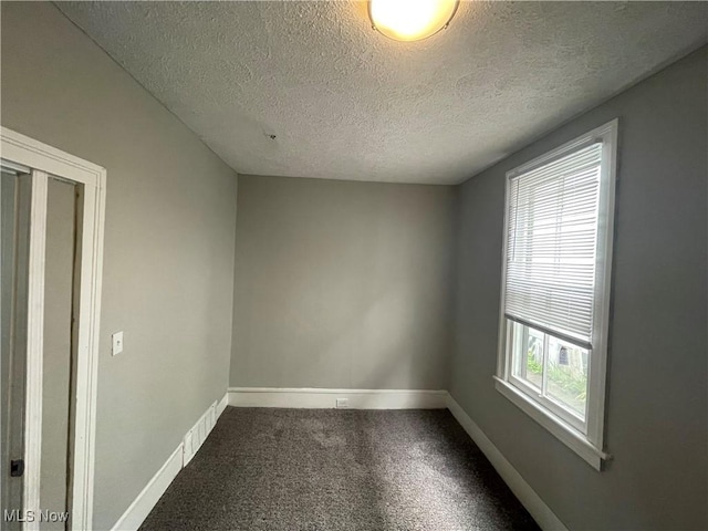 carpeted empty room with visible vents, baseboards, and a textured ceiling