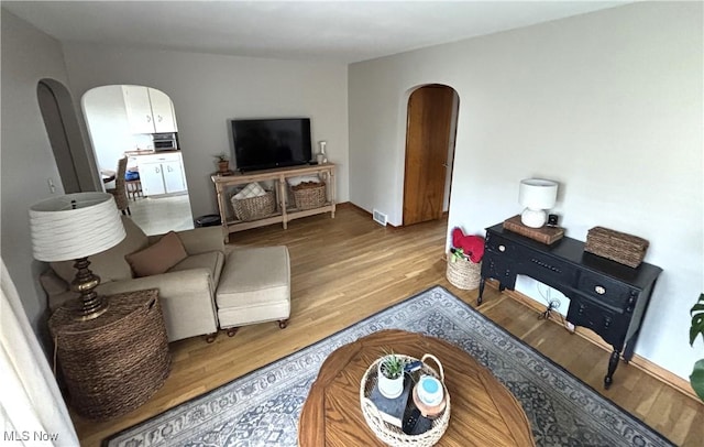 living room featuring visible vents, wood finished floors, and arched walkways