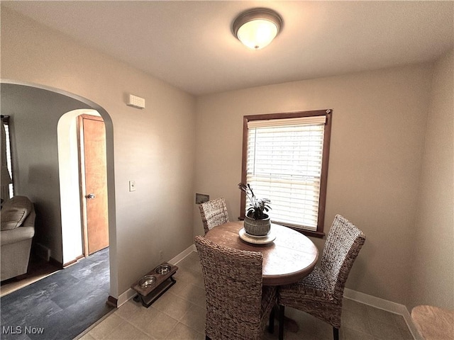 dining room with baseboards and arched walkways