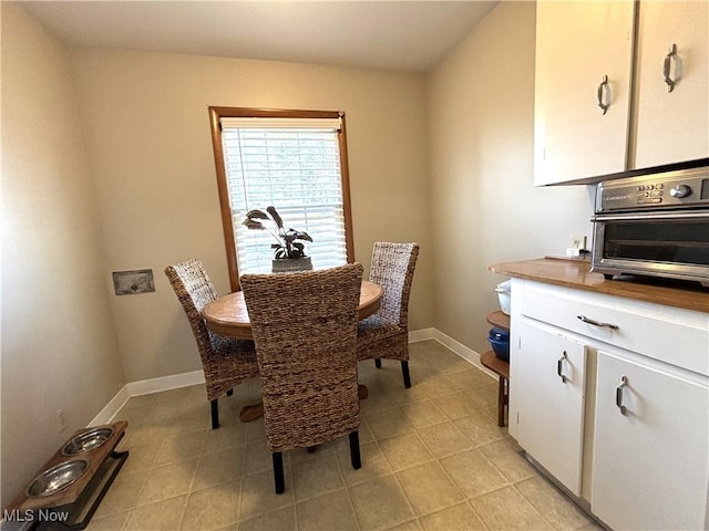 dining room featuring baseboards, light tile patterned flooring, and a toaster