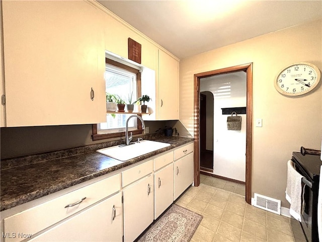 kitchen with baseboards, visible vents, a sink, white cabinets, and dark countertops