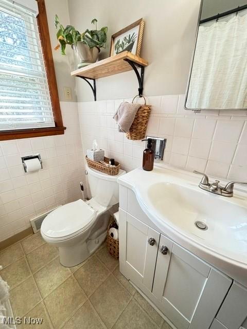 bathroom with tile patterned floors, toilet, tile walls, and vanity