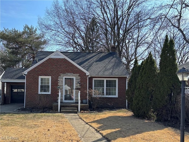 view of front of home featuring roof with shingles, a chimney, a front lawn, a garage, and brick siding