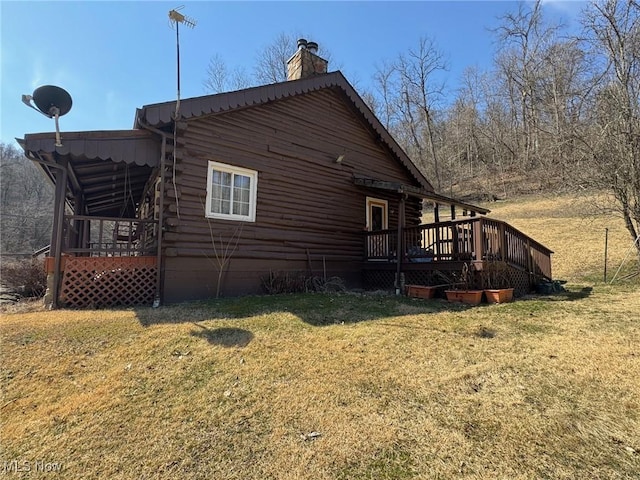 view of side of property featuring log siding, a deck, and a yard