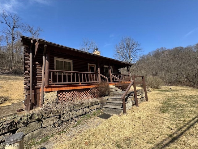 log home with log exterior, a chimney, and a wooden deck