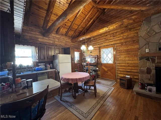 dining area featuring light wood finished floors, beamed ceiling, wooden ceiling, rustic walls, and high vaulted ceiling