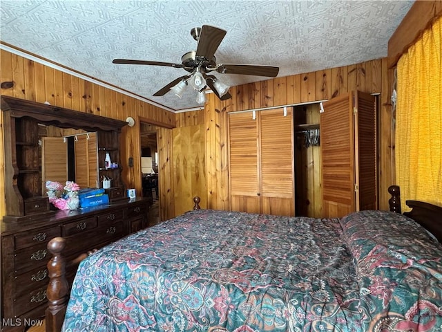 bedroom with a closet, wooden walls, a ceiling fan, and a textured ceiling