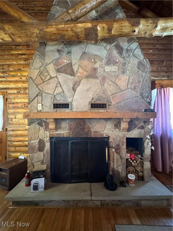 room details featuring rustic walls, a stone fireplace, and wood finished floors