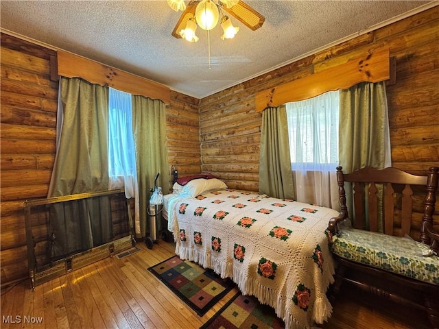 bedroom with visible vents, a textured ceiling, ceiling fan, and wood-type flooring