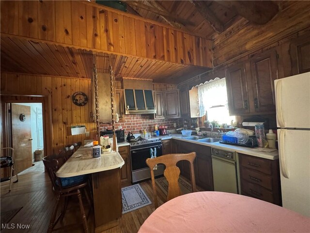 kitchen with range with gas stovetop, freestanding refrigerator, a sink, light countertops, and wooden ceiling