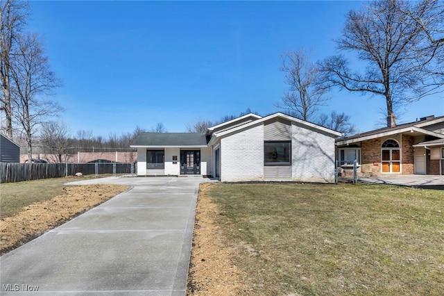 mid-century home featuring brick siding, concrete driveway, fence, and a front lawn