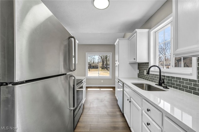 kitchen featuring decorative backsplash, stainless steel appliances, dark wood-style floors, white cabinetry, and a sink