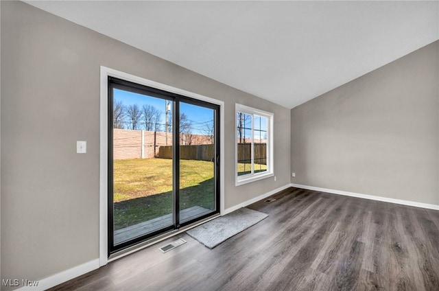 unfurnished room featuring dark wood-type flooring, visible vents, baseboards, and vaulted ceiling