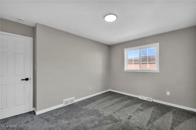 empty room featuring visible vents, baseboards, and dark colored carpet