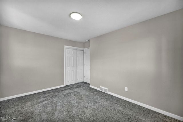 unfurnished bedroom featuring a closet, baseboards, visible vents, and dark carpet