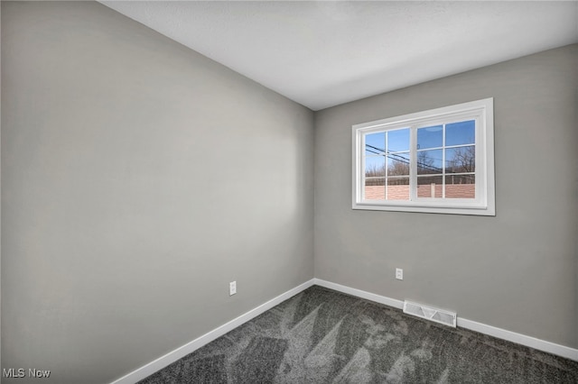 unfurnished room featuring dark colored carpet, visible vents, and baseboards