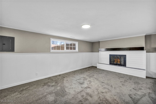 unfurnished living room with electric panel, a glass covered fireplace, wainscoting, and carpet floors