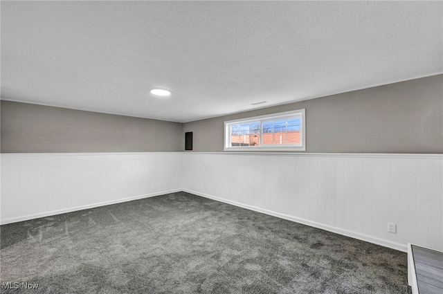 basement featuring carpet, wainscoting, and a textured ceiling