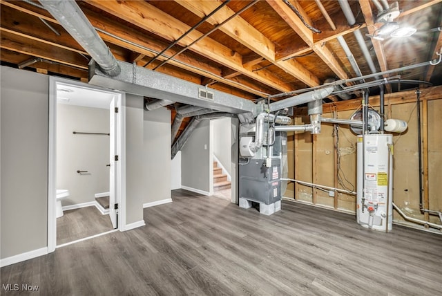 below grade area featuring visible vents, stairway, water heater, wood finished floors, and heating unit