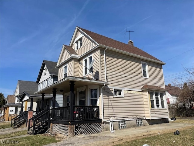 view of side of home featuring a porch and a chimney