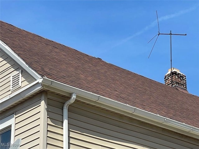 exterior details featuring a downspout, gutters, and roof with shingles