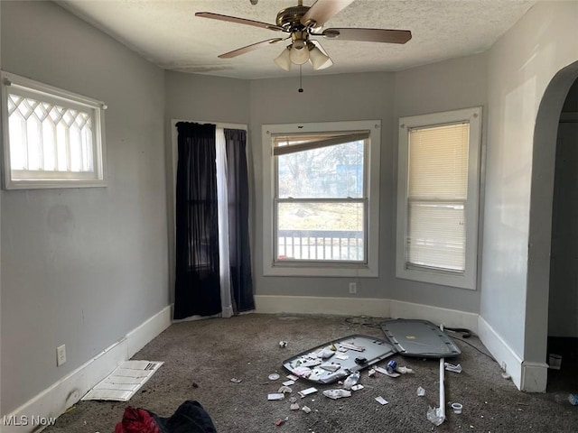 spare room with ceiling fan, a healthy amount of sunlight, arched walkways, and a textured ceiling