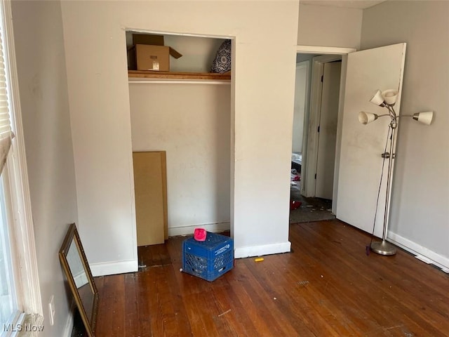 unfurnished bedroom featuring a closet, baseboards, and hardwood / wood-style floors