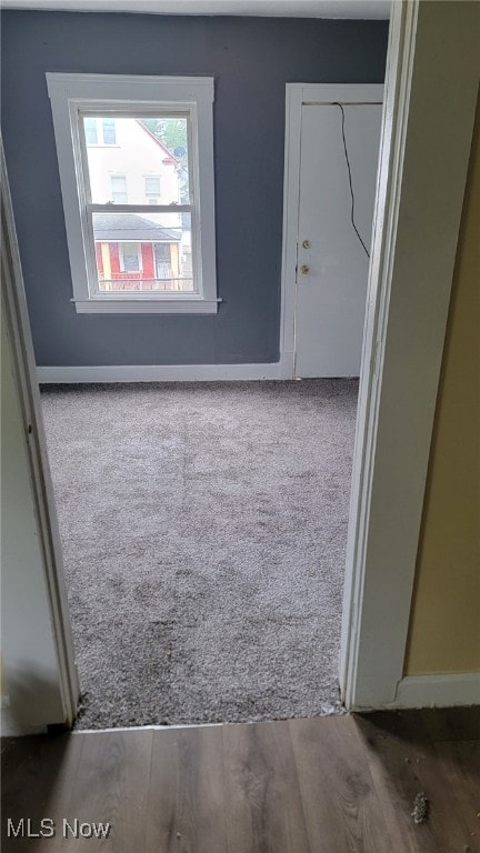 carpeted spare room with baseboards and wood finished floors