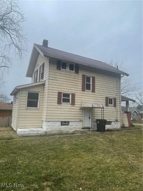 back of property featuring a lawn and a chimney