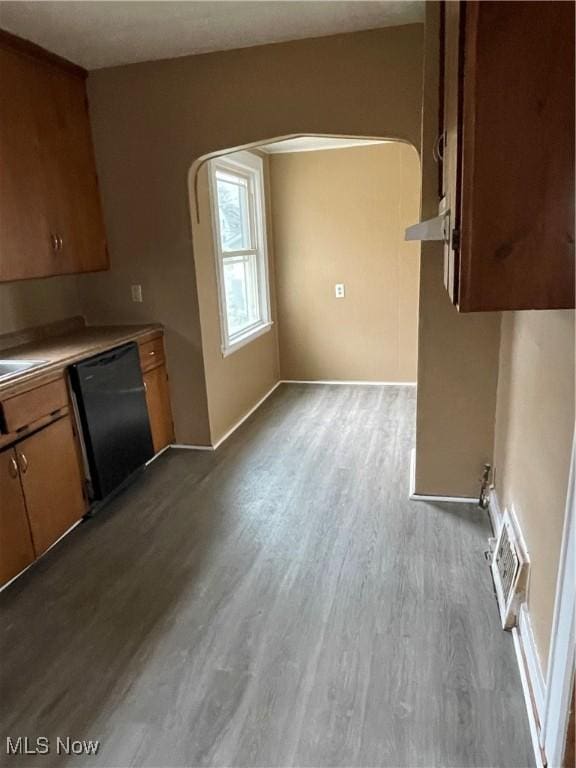 kitchen featuring wood finished floors, visible vents, arched walkways, light countertops, and black dishwasher