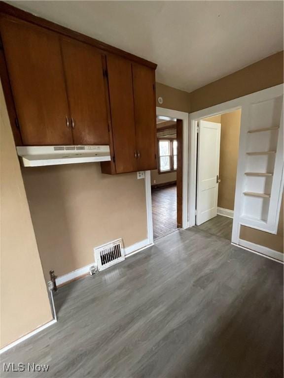 clothes washing area with visible vents, dark wood-type flooring, and baseboards