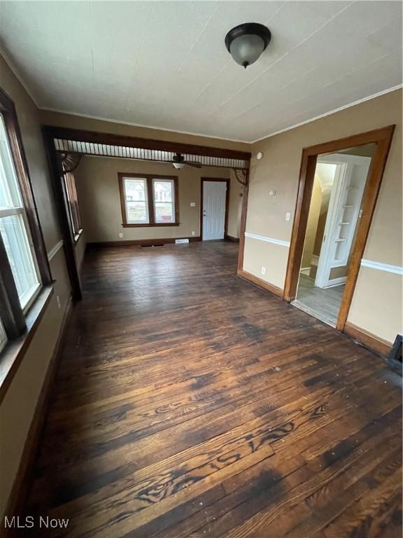 spare room with baseboards, dark wood finished floors, and ornamental molding