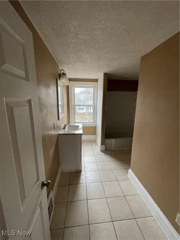 bathroom with vanity, baseboards, visible vents, tile patterned flooring, and a textured ceiling