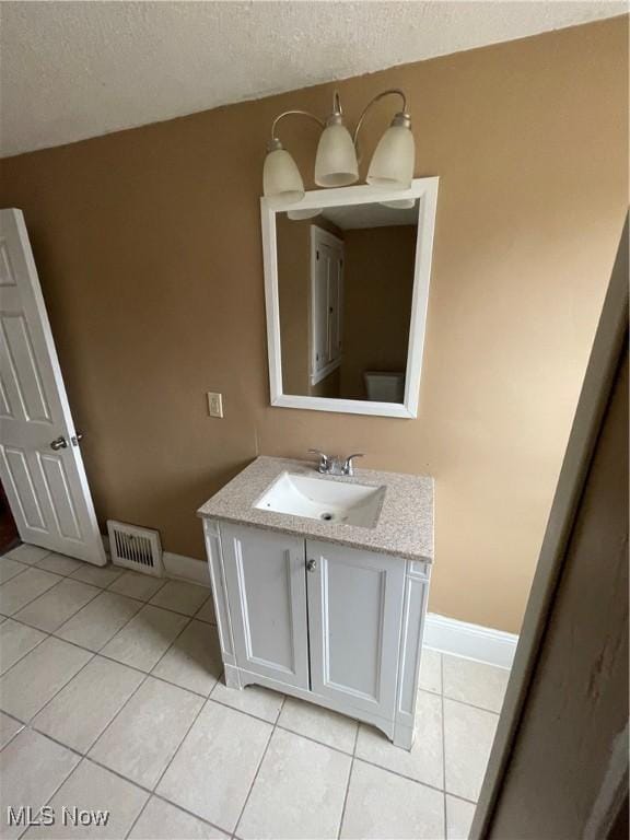 bathroom featuring tile patterned flooring, visible vents, baseboards, vanity, and a textured ceiling