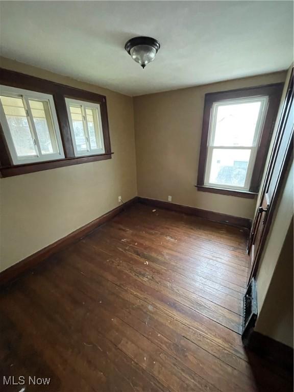 unfurnished room featuring dark wood-style floors and baseboards