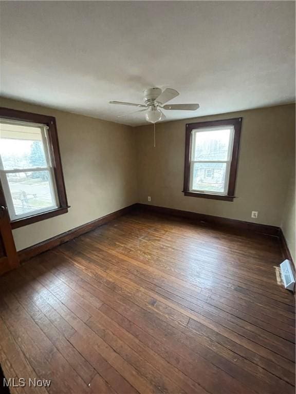 unfurnished room with visible vents, a ceiling fan, dark wood-type flooring, and baseboards