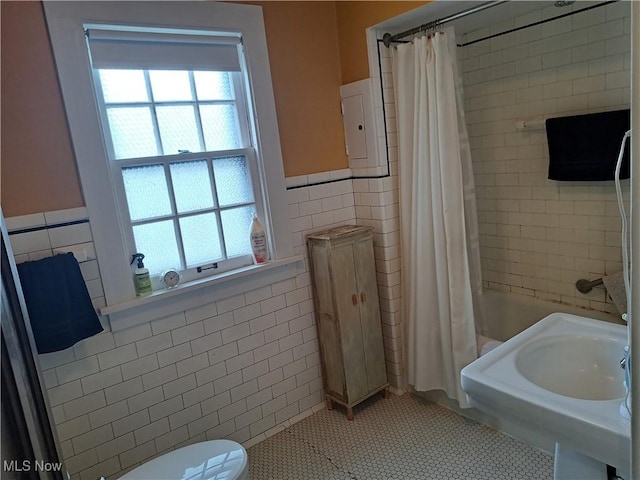 bathroom with tile walls, toilet, a healthy amount of sunlight, and wainscoting