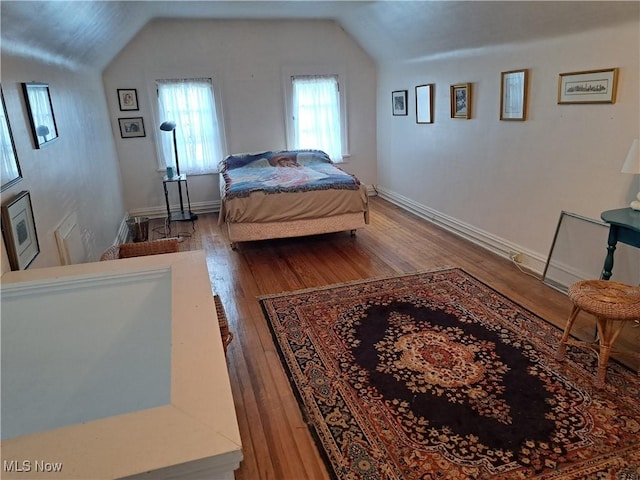 bedroom with baseboards, lofted ceiling, and wood finished floors