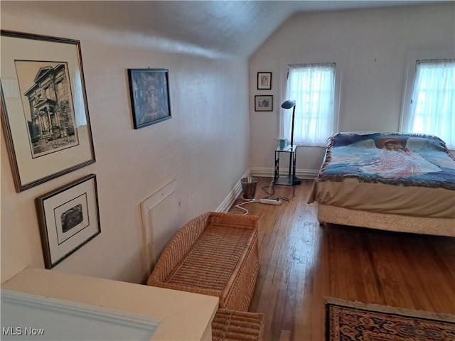 bedroom featuring baseboards, multiple windows, wood-type flooring, and vaulted ceiling