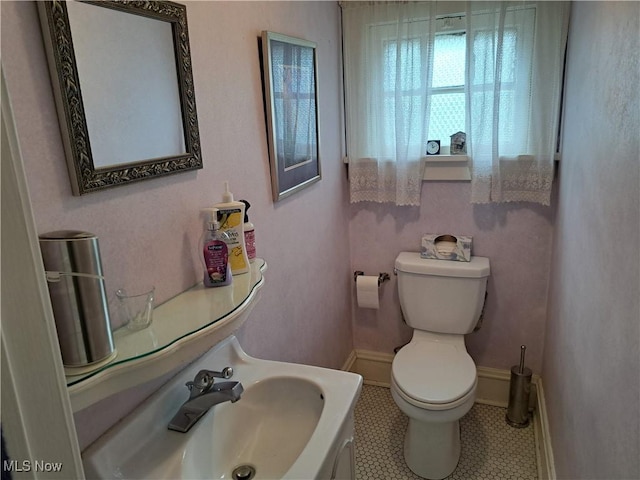 bathroom with tile patterned flooring, toilet, baseboards, and a sink